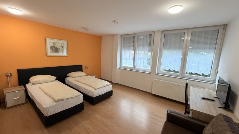 Extra großes Zweibettzimmer mit Sofa und orangefarbener Wand